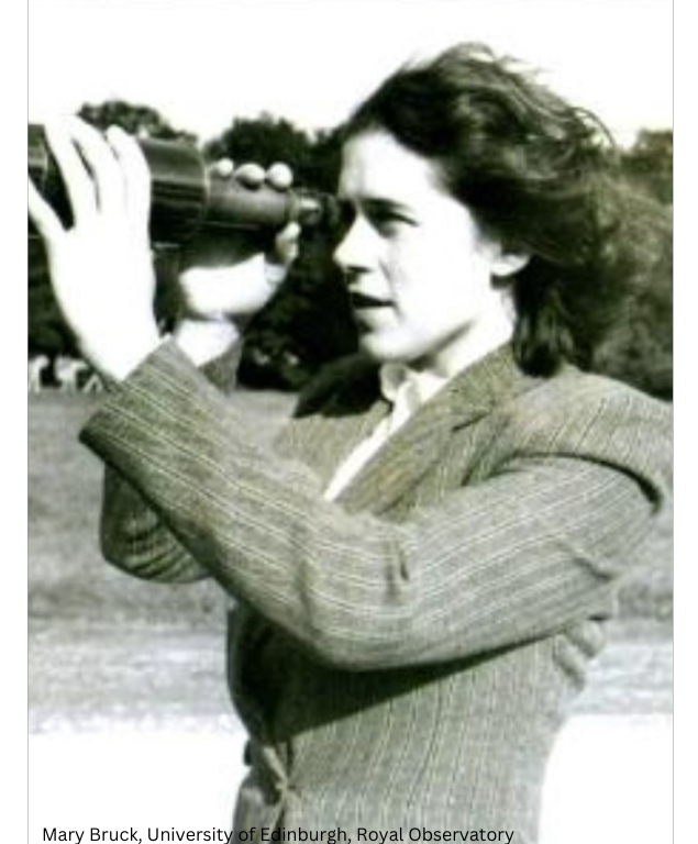 A woman, dressed in  a wool suit jacket with dark wavy hair, looking through a telescope.