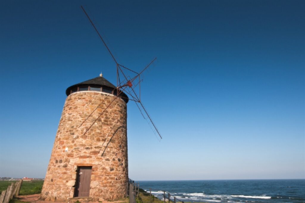 Tan stone windmill set against a blue sky.