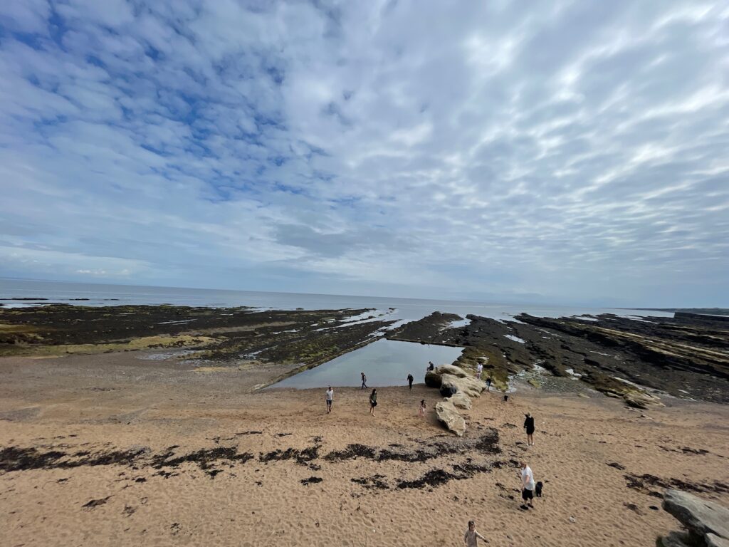 Looking outwards to the ocean, tidal pool with a rocky shore and low clouds above.