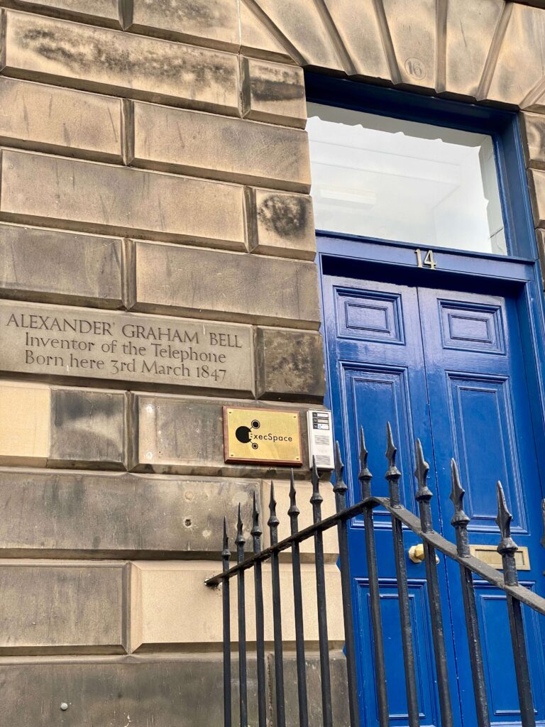 On the left: an engraved stone marking Bell's birthplace; on the right a black iron fence and a roayl blue door reading No. 14.