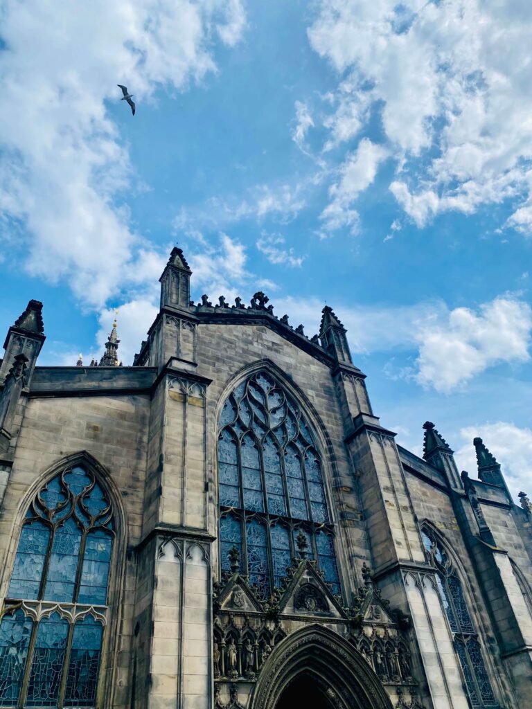 Limestone cathedral with ornate spires and windows against a blue sky with wispy coulds.