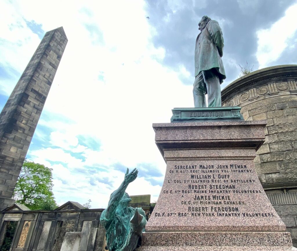 Engraved names of fallen soldiers; Lincoln, the slave, and a a tall stone obelisk are also in the frame.