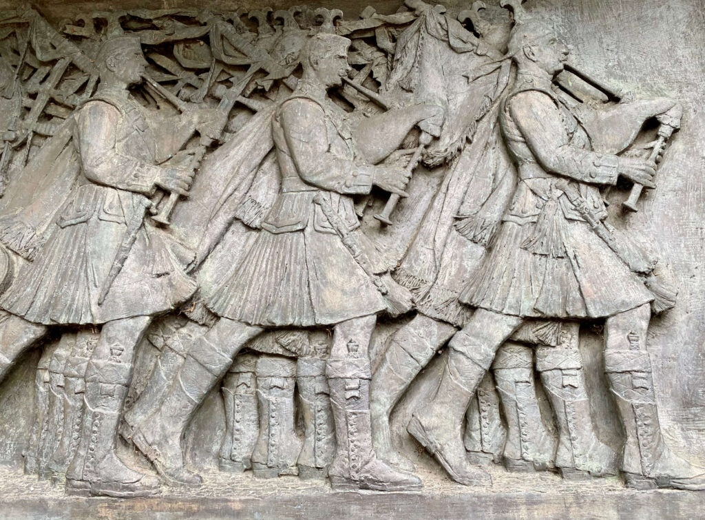 Relief of kilted Scots walking with bagpipes.